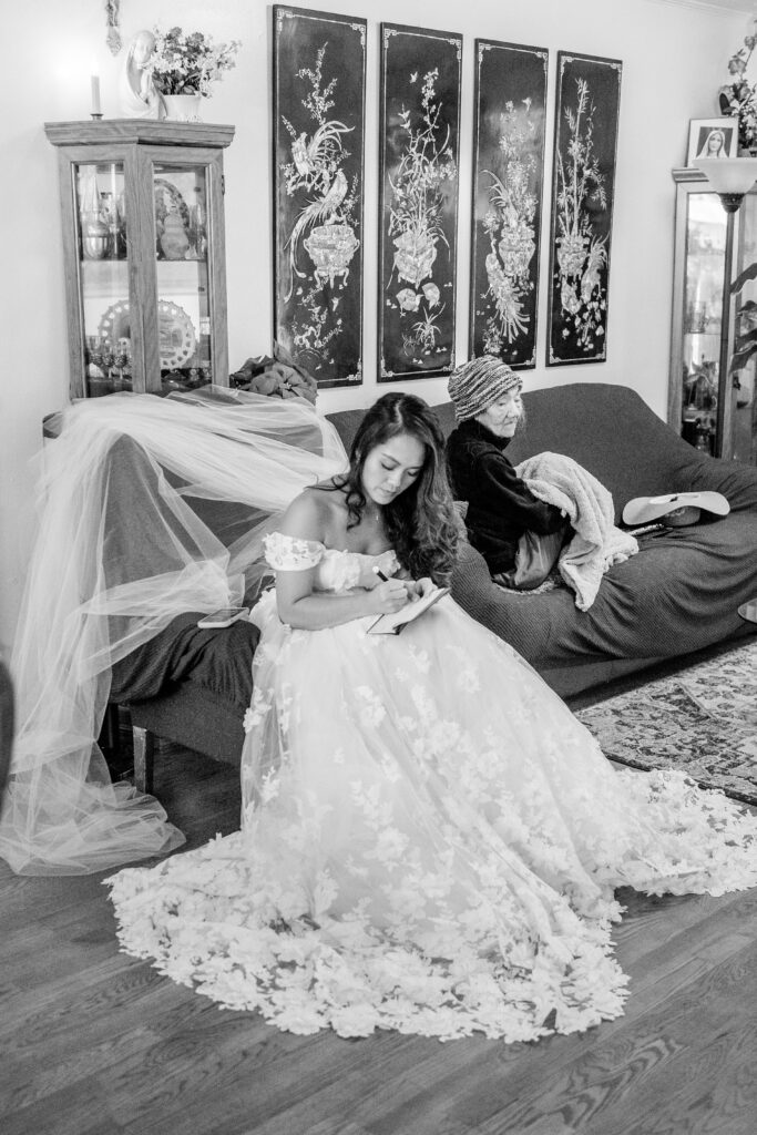 A bride on the couch next to her grandmother as she writes a letter to the groom