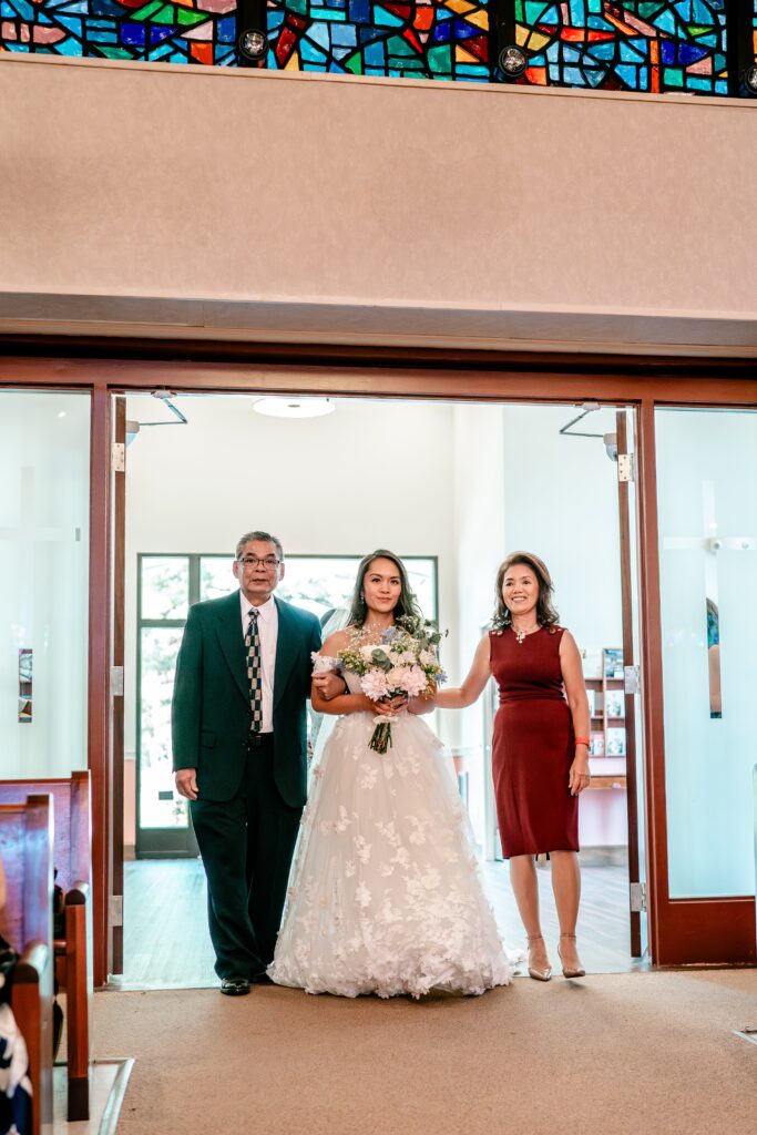 A bride walking down the aisle for a St. John the Beloved wedding
