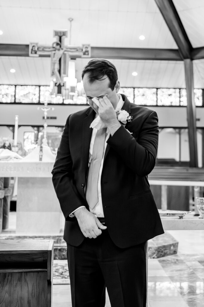 A groom wipes away tears at the start of the wedding ceremony