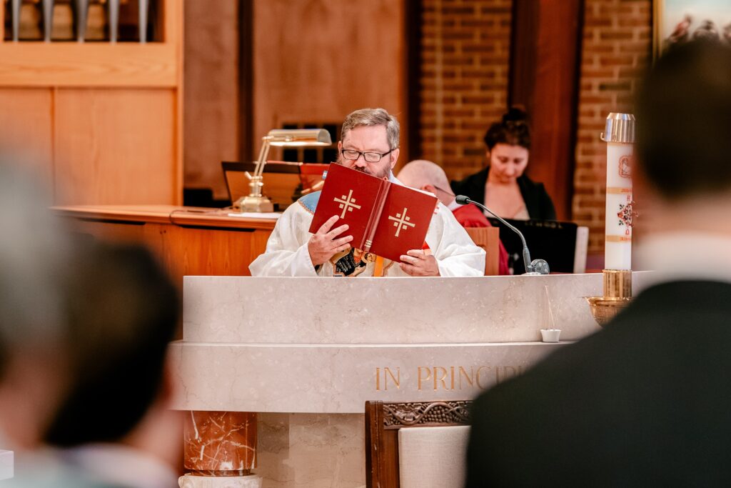 A priest kisses the gospel during a church ceremony before a Murray Hill wedding