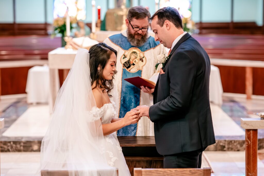 A bride and groom exchange rings inside the church before their Murray Hill wedding