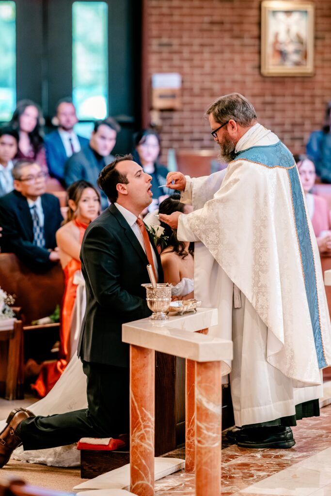 A groom receiving communion during his Catholic wedding
