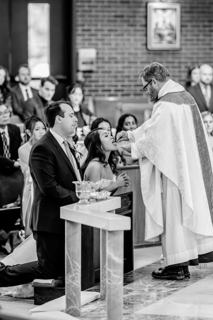 A bride receiving communion at the church before her Murray Hill wedding
