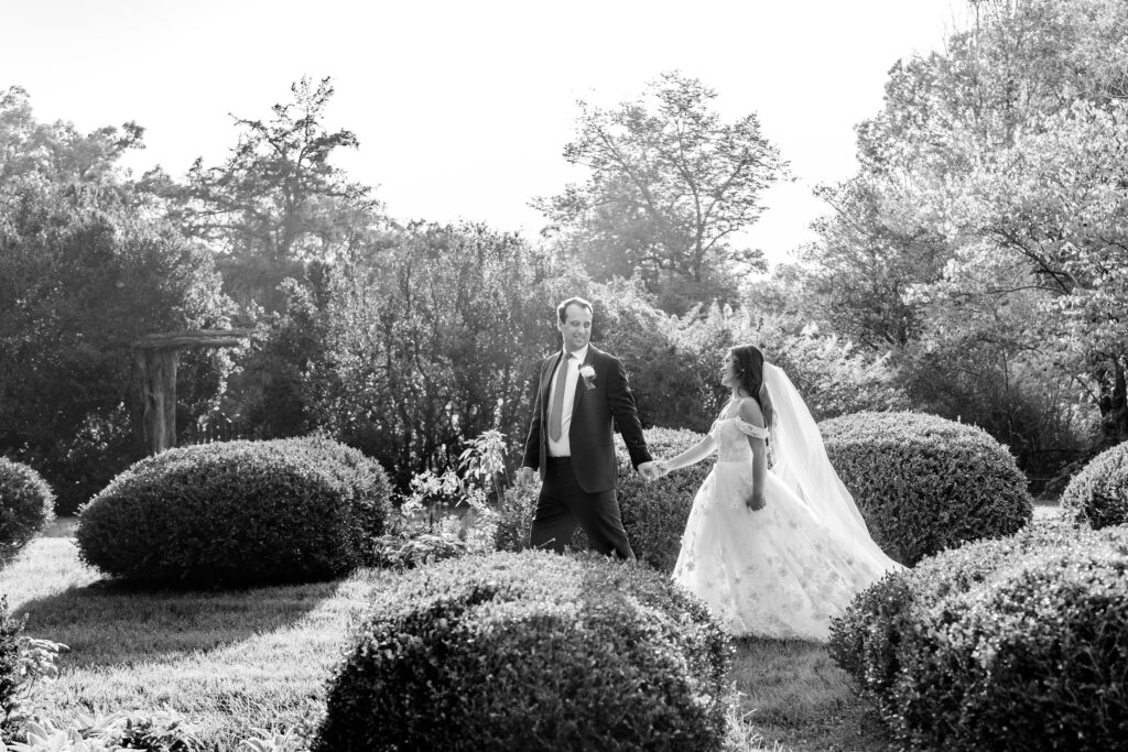 A bride and groom walking together through the garden