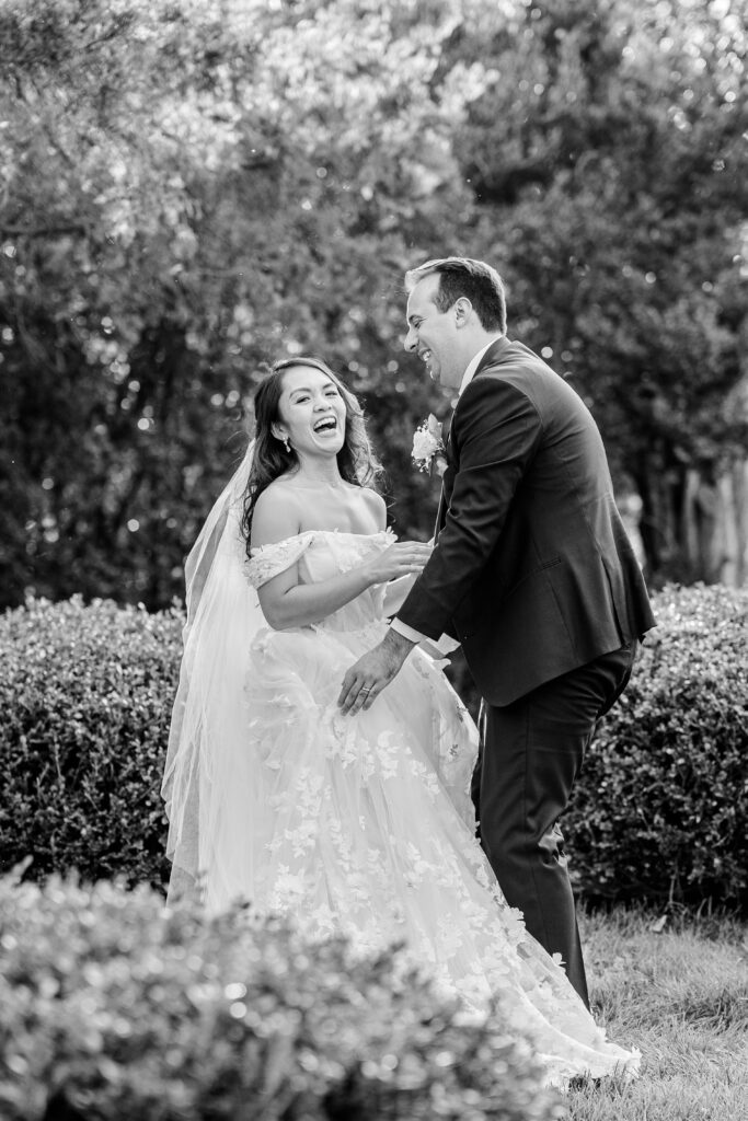 A bride and groom laugh together in the garden during their Murray Hill wedding