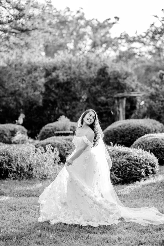 A bride twirls her skirt and smiles over her shoulder while in the garden for a Murray Hill wedding