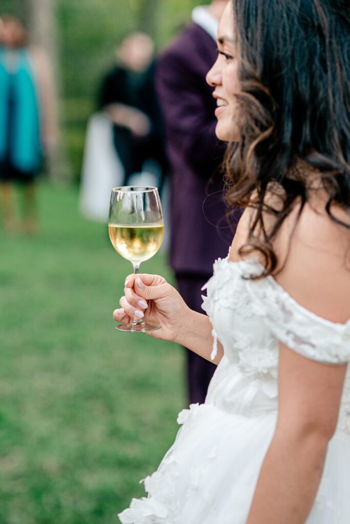 A bride holding a glass of wine at cocktail hour