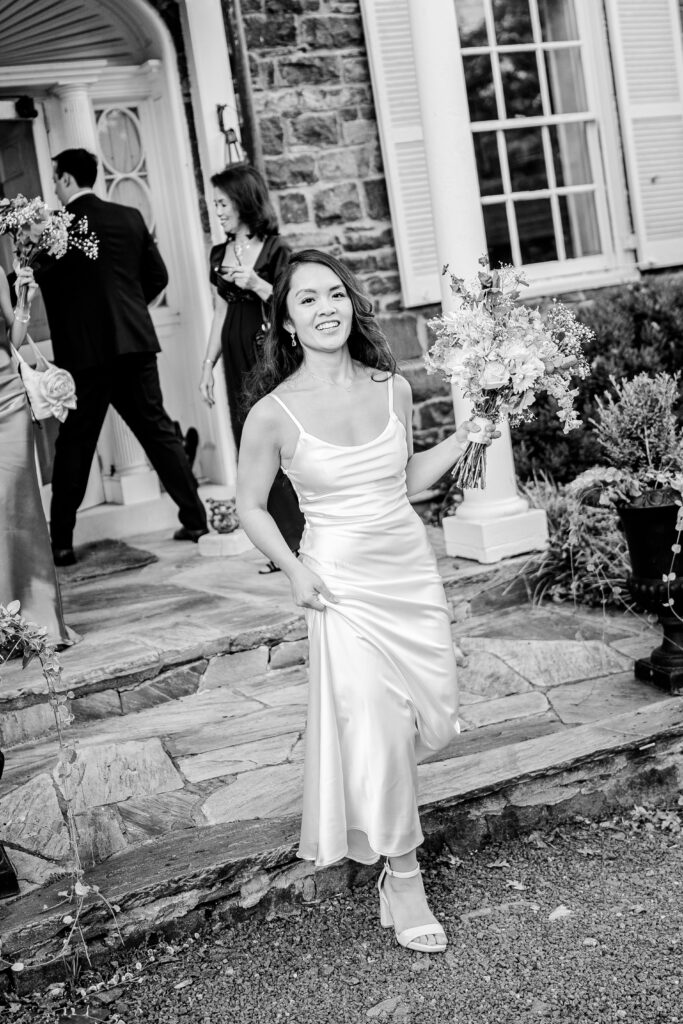 A bride stepping out of the manor house in her reception dress during her Murray Hill wedding