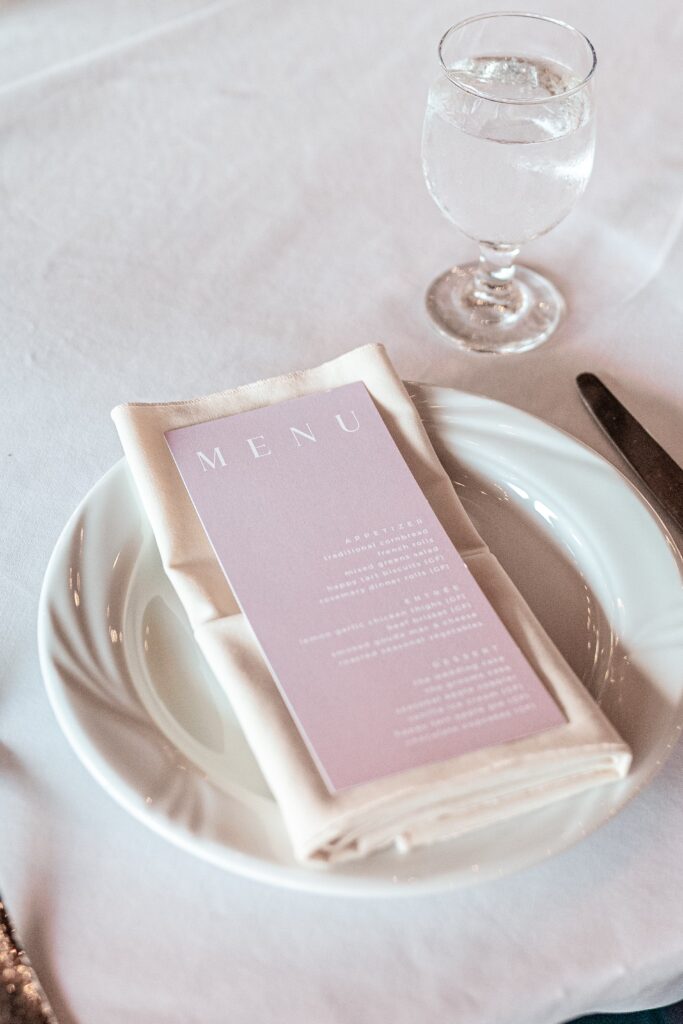 A pink menu on an ivory napkin for a wedding reception