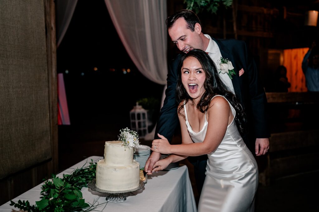 A bride smiling over her shoulder during her cake cutting at a Murray Hill wedding reception