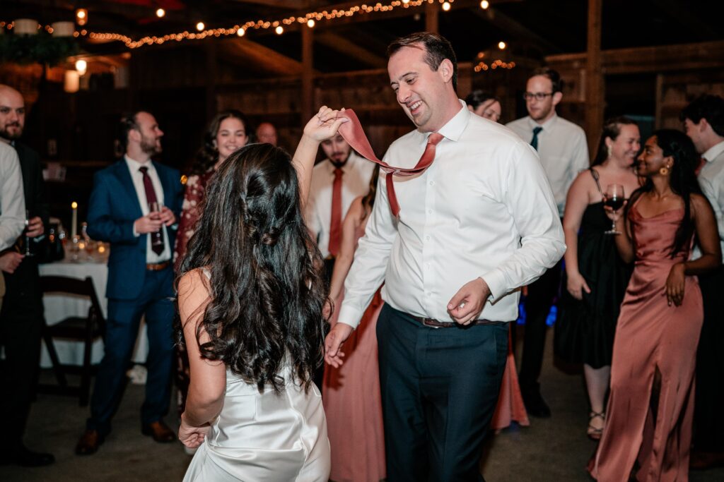 A bride grabbing her groom's tie on the dance floor of their reception