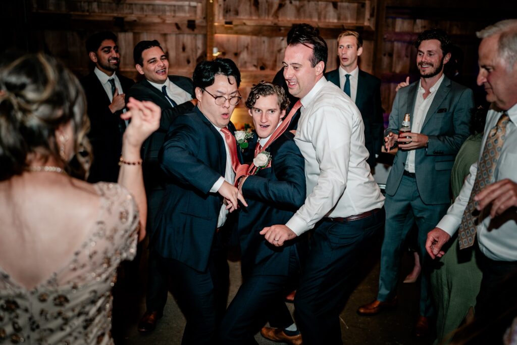 The groom and groomsmen dancing together at the reception after a St. John the Beloved wedding