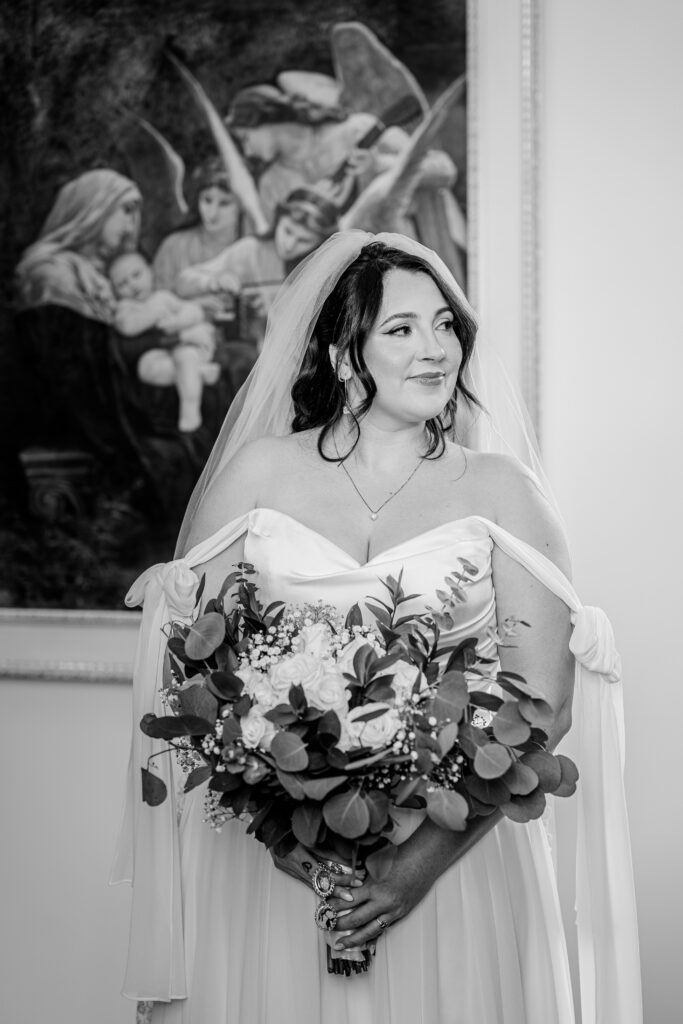 A bride looking off to the side while posed in front of a romantic painting during her Loudoun County wedding