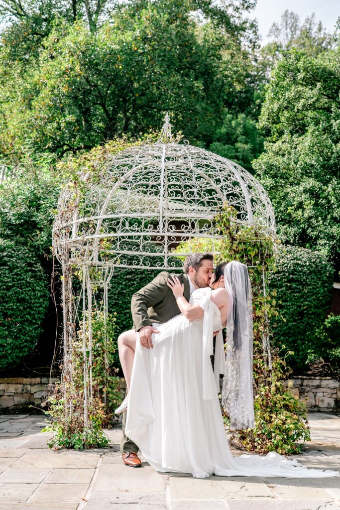 A bride and groom share a romantic dip kiss during their Stone Manor Boutique Inn wedding