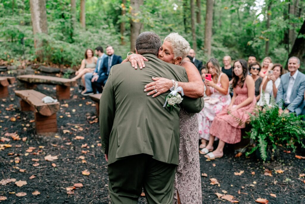A groom's mom gives him a hug at the beginning of his ceremony for a Stone Manor Boutique Inn wedding