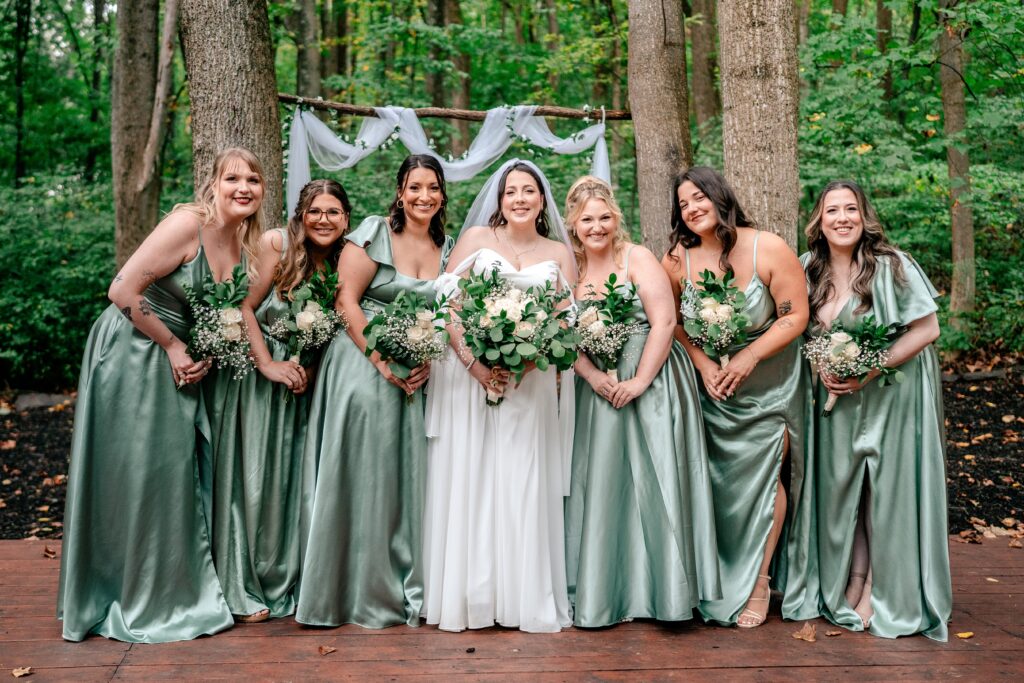 A bride and her bridesmaids in mint green smiling together
