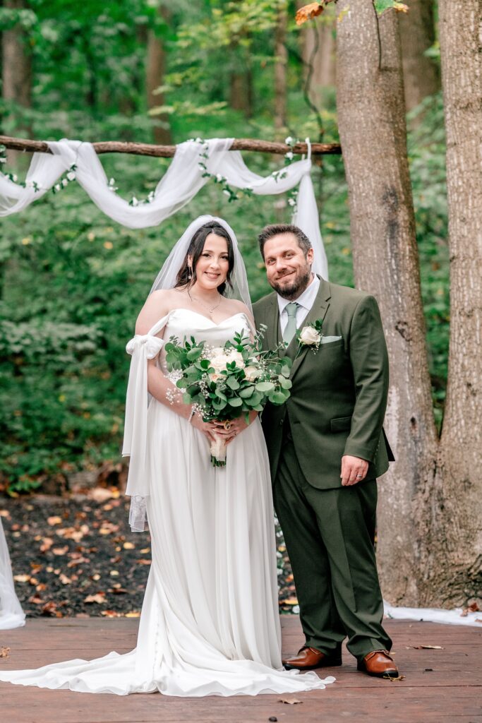 A classic portrait of a bride and groom smiling for a portrait at their outdoor ceremony site