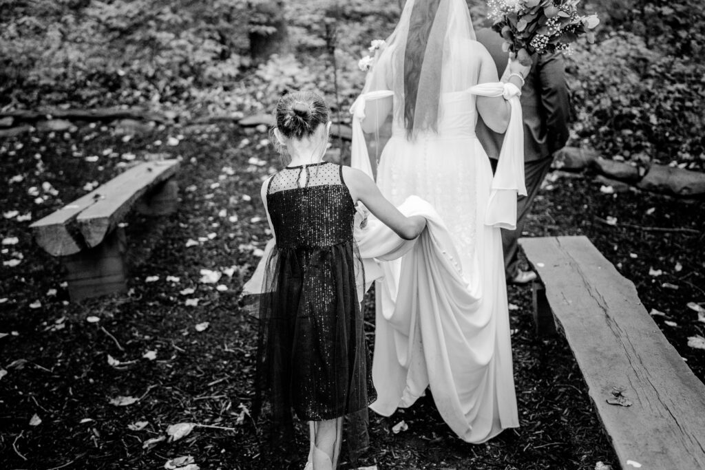A girl helping the bride with her train during a Stone Manor Boutique Inn wedding