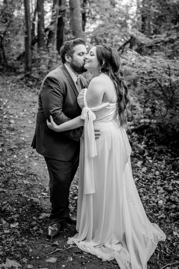 A groom kisses his bride on the cheek during their Stone Manor Boutique Inn wedding
