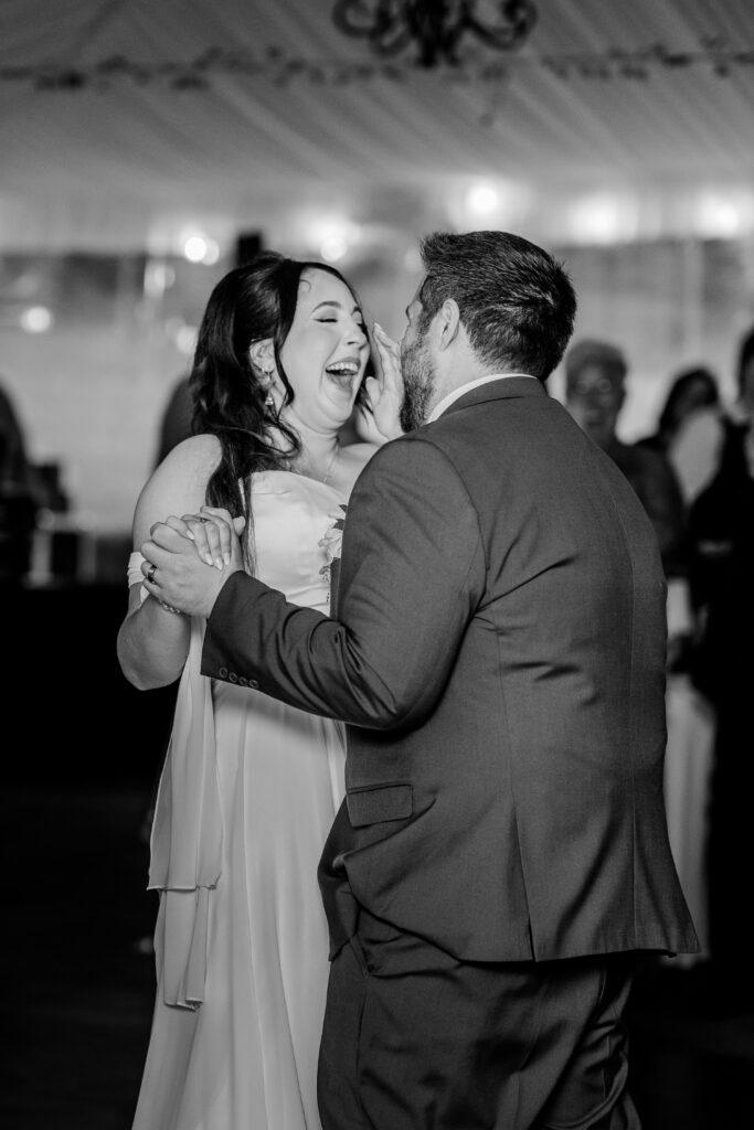 A Northern VA wedding photographer image of a bride laughing during her first dance with her groom