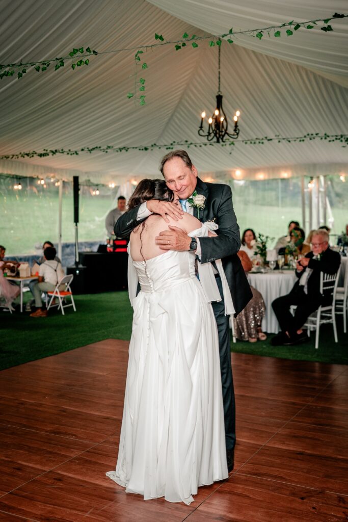 A bride's dad gives her a hug as they share their father daughter dance