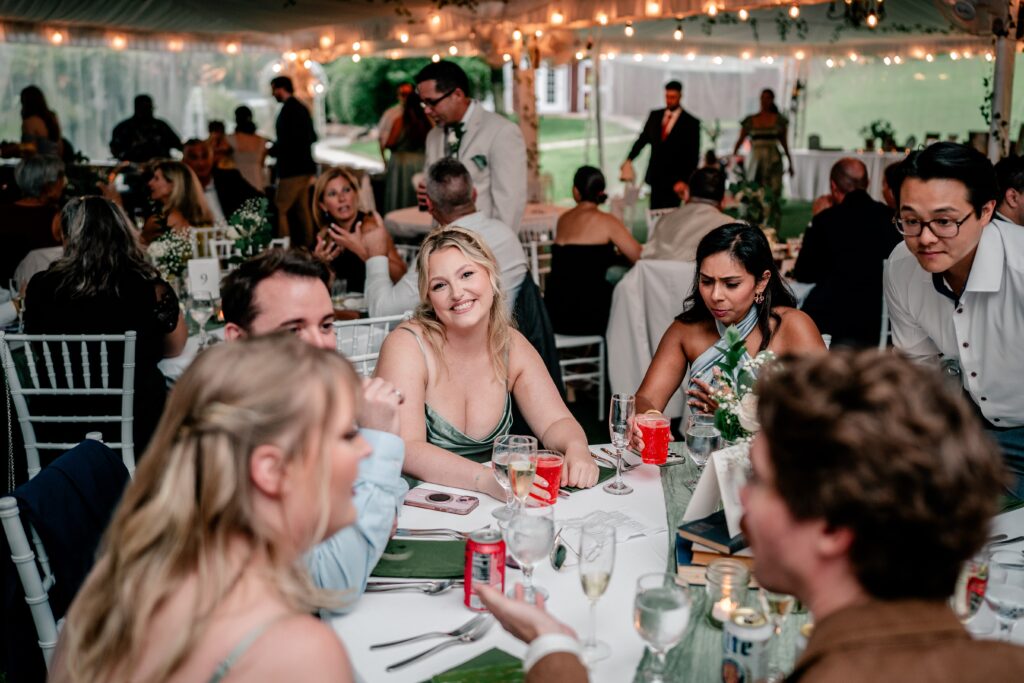 Wedding guests smiling at their tables during a tented Stone Manor Boutique Inn wedding reception