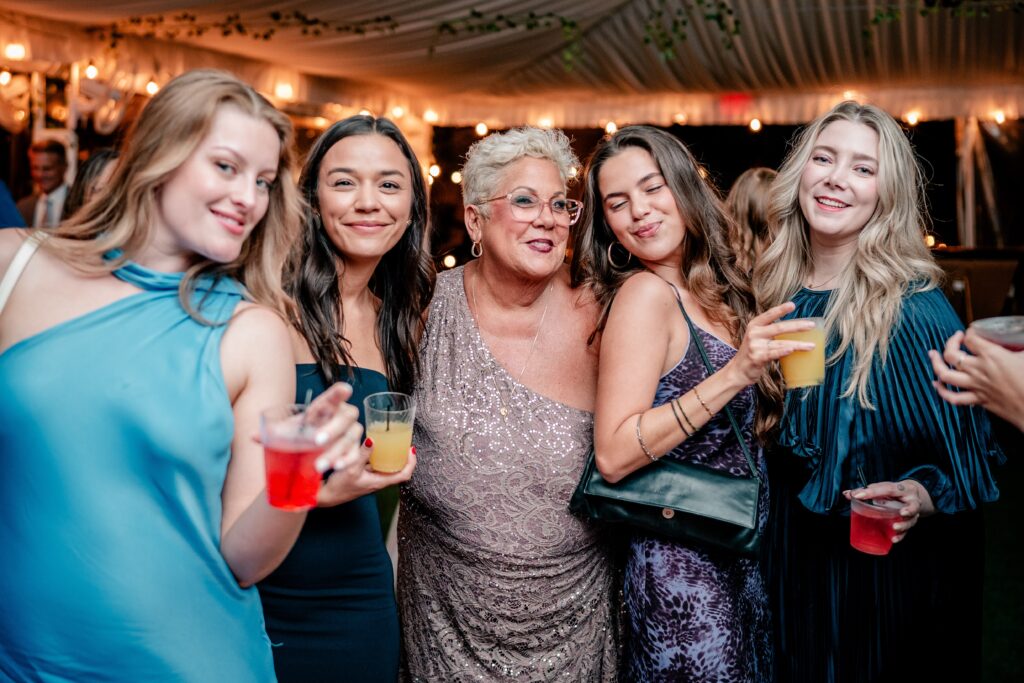 The mother of the groom surrounded by the bride's friends during a Stone Manor Boutique Inn wedding reception