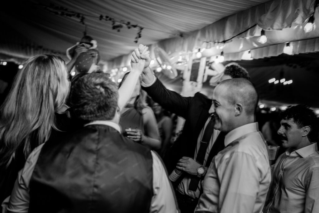 Wedding guests clasp hands in the air on the dance floor