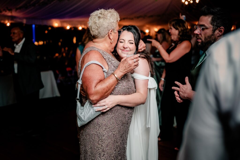The mother of the groom kissing the bride on the side of her head during her Stone Manor Boutique Inn wedding