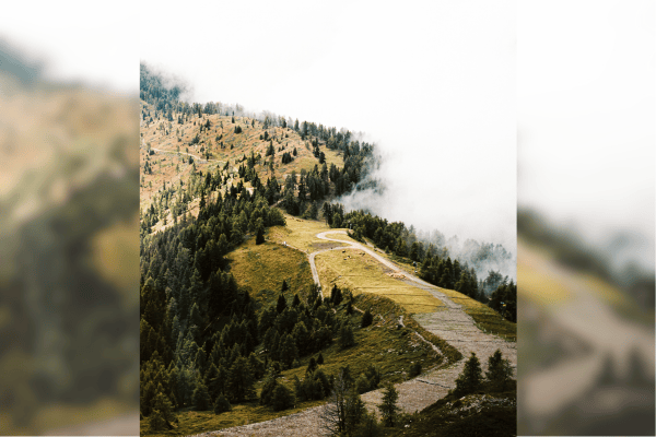 A 35mm film image of a mountainside with fog rolling in as viewed from above the mountain in an image featured in Trivium Magazine