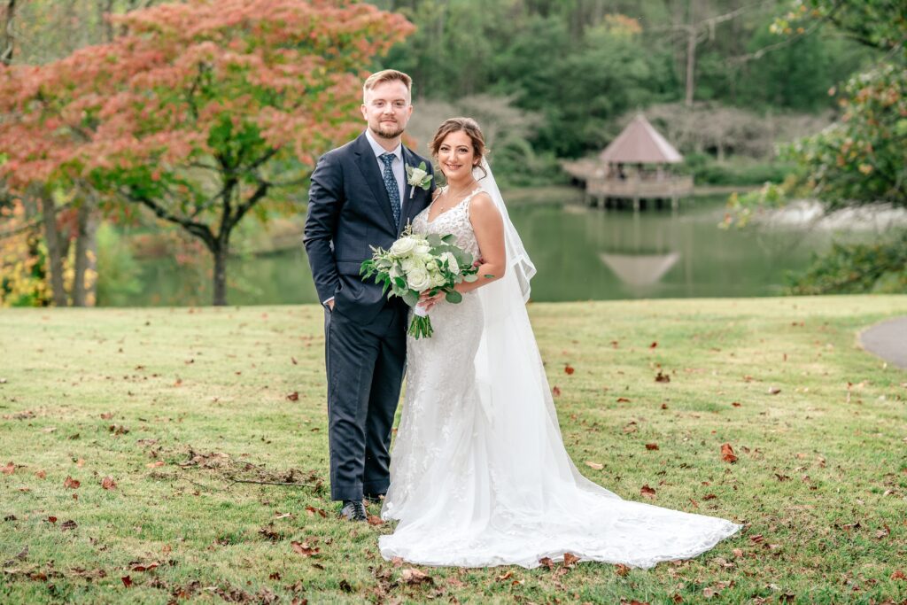 A bride and groom posed in front of a lake
