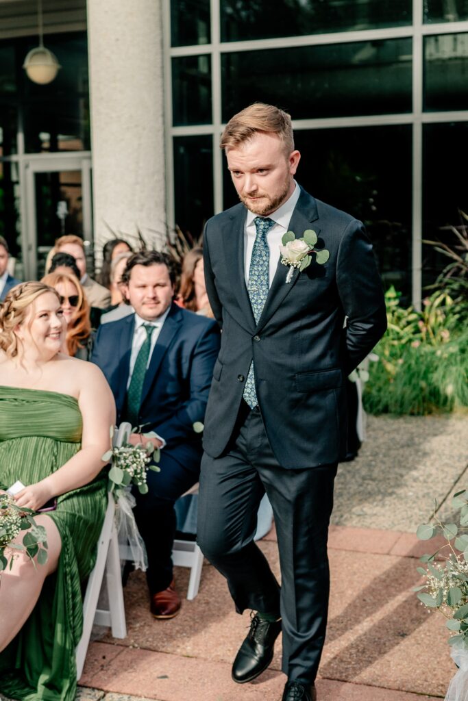 A groom walks stoically into his wedding ceremony