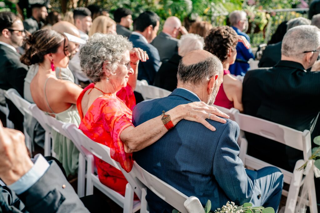 A wedding guest with her arm around her husband during a ceremony