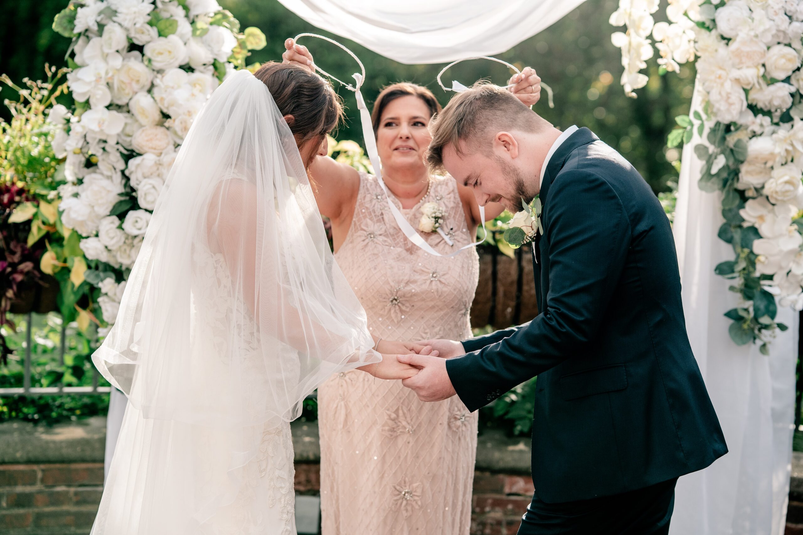 A bride and groom perform the Orthodox crowning ritual during their Atrium at Meadowlark wedding