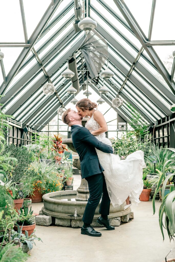 A bride and groom share a dramatic kiss inside a greenhouse for an Atrium at Meadowlark wedding
