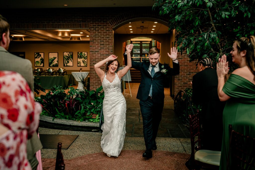 A bride and groom waving as they enter their Meadowlark Botanical Gardens wedding reception