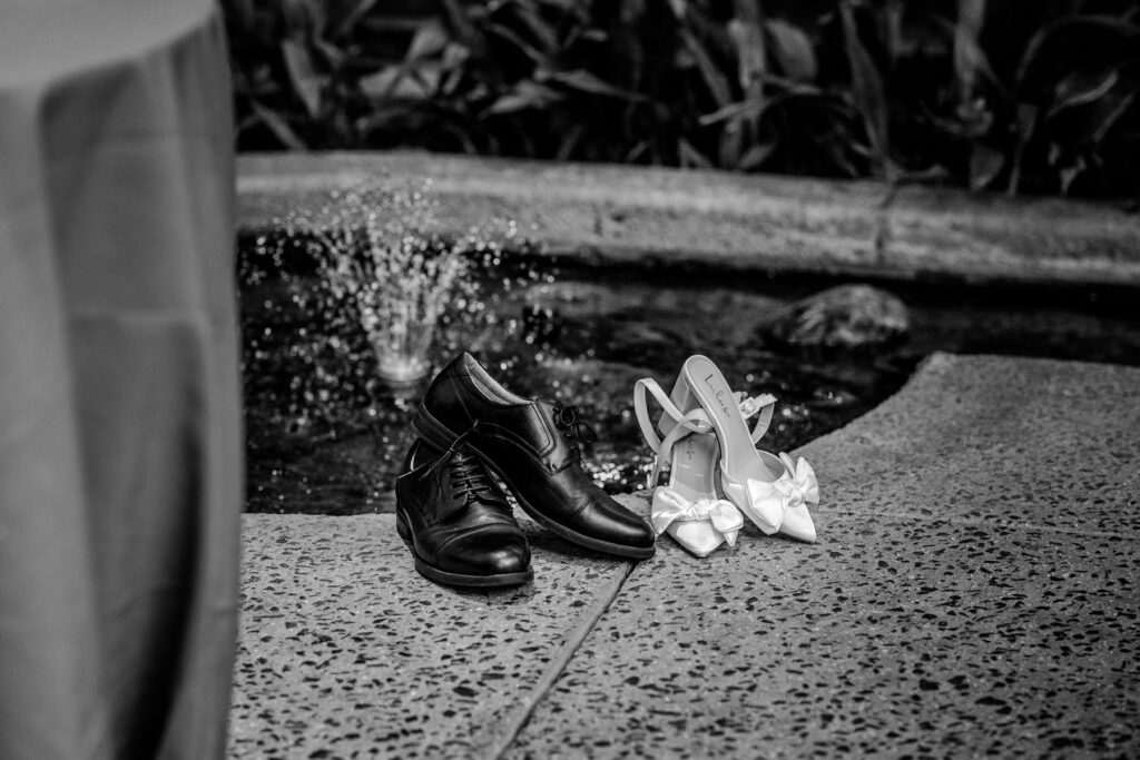 The bride and groom's formal shoes placed neatly beside a small fountain at their wedding reception