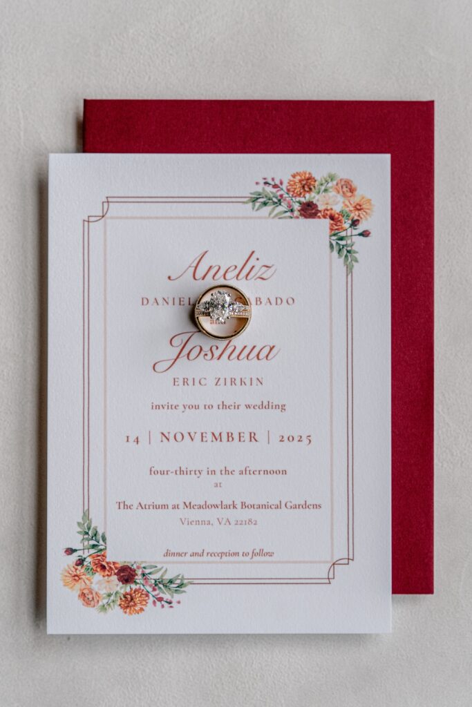 A set of wedding rings resting on top of a wedding invitation before a Meadowlark Botanical Gardens fall wedding