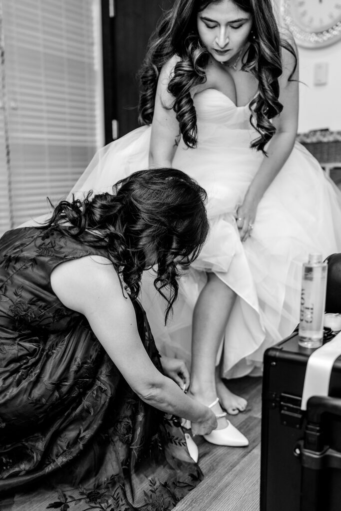 A bride's mom helping her put on her shoes