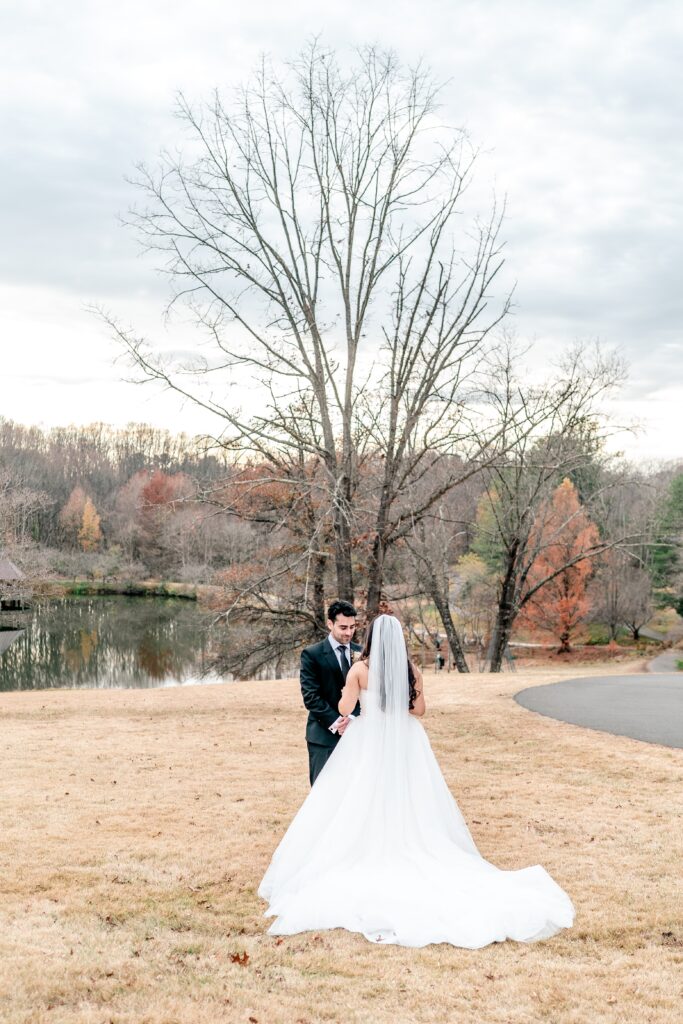 A bride and groom's first look in front of a lake coordinated by their Northern VA wedding photographer
