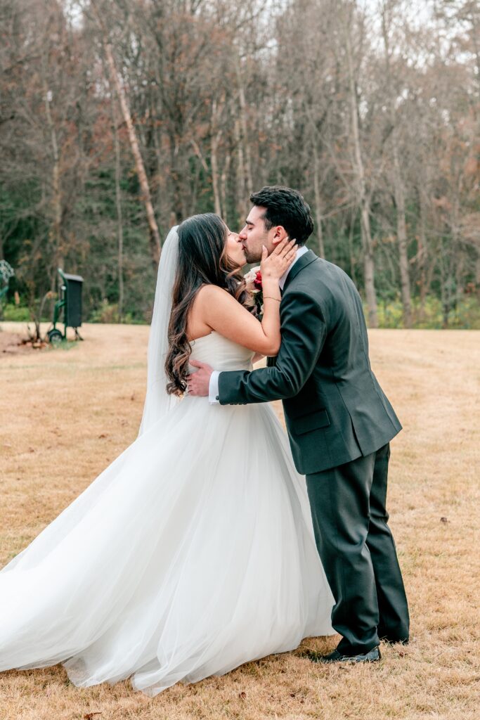 A bride and groom share a kiss on the lawn before their Atrium at Meadowlark indoor wedding