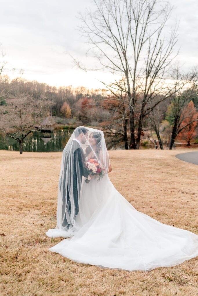 A bride and groom smile under the veil during their Meadowlark Botanical Gardens fall wedding