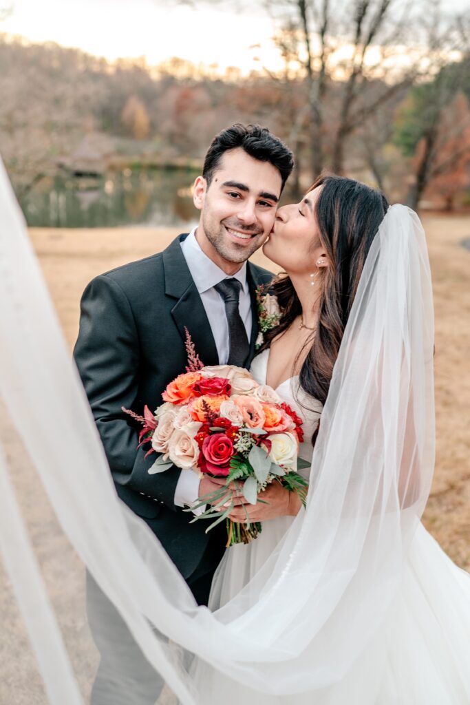 A bride kisses her groom on the cheek during their Meadowlark Botanical Gardens fall wedding