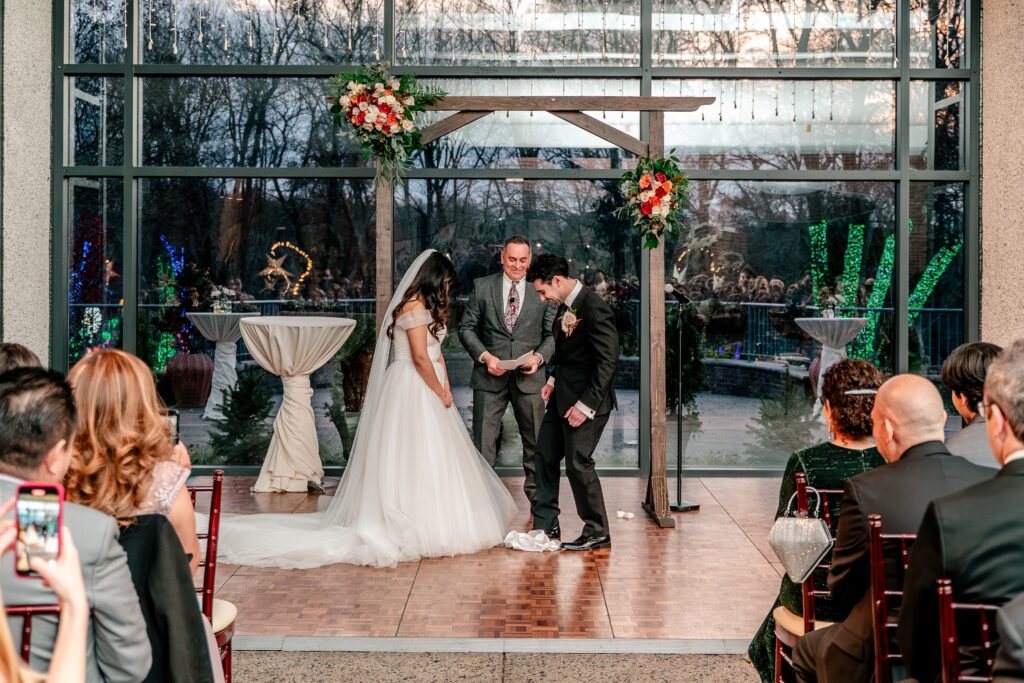 A groom stepping on the glass at the end of his Meadowlark Botanical Gardens fall wedding ceremony indoors