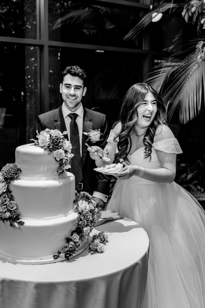A bride and groom laugh during their cake cutting for their Atrium at Meadowlark indoor wedding