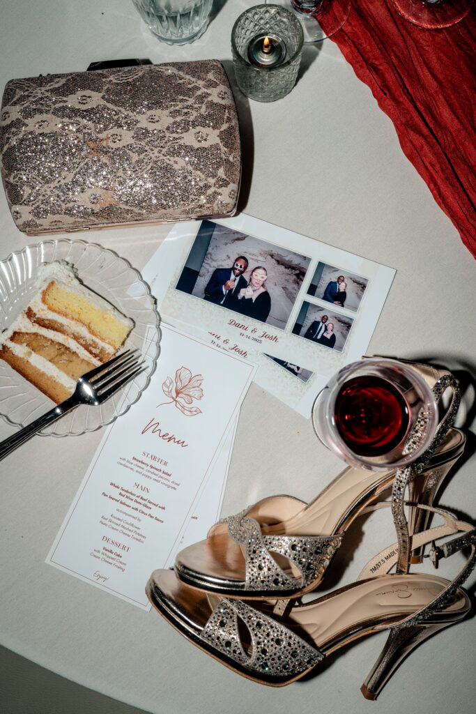 A table set with cake, shoes, menus, and Photo Booth pictures at a Meadowlark Botanical Gardens fall wedding reception