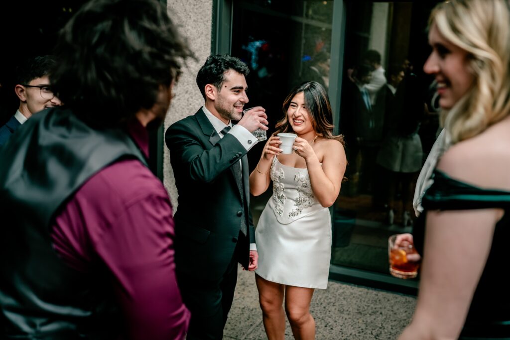 A bride sips coffee and smiles at her groom during their reception