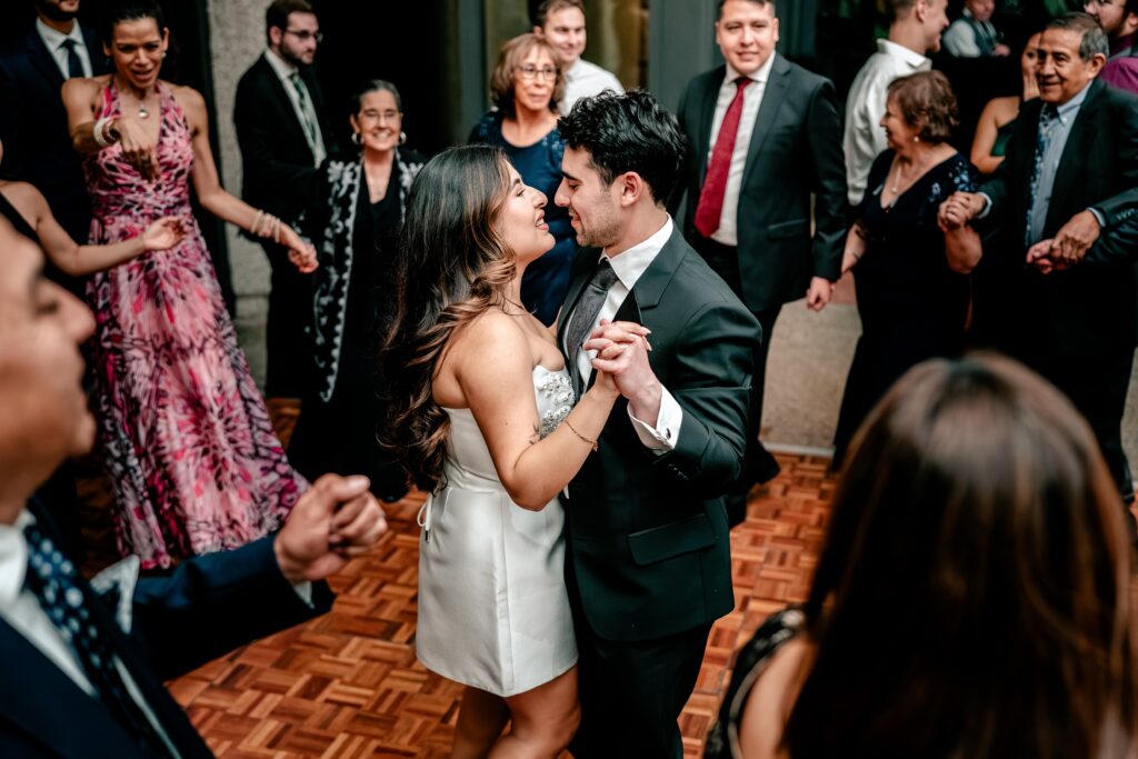 A bride and groom dance surrounded by guests at their wedding reception