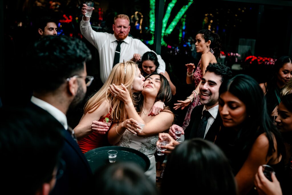 A guest kissing the bride on the cheek as they dance during her Meadowlark Botanical Gardens fall wedding