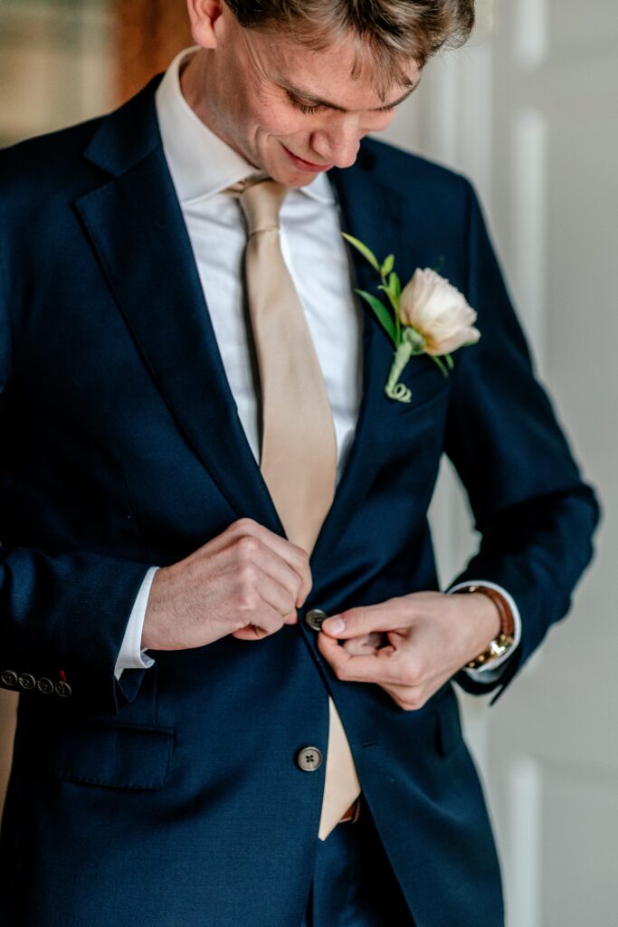 A groom buttoning his jacket for his Catholic wedding photographer